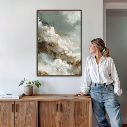 A woman in a white blouse and blue jeans stands next to a wooden cabinet, leaning against it and looking to the side. Above her, a framed painting of clouds hangs on the wall.