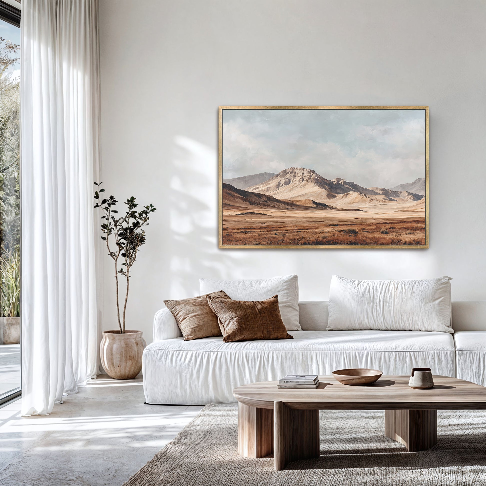 a serene living room with a large painting of a desert landscape hanging on the wall. The room is furnished with a white sofa and a wooden coffee table, creating a cozy and inviting atmosphere.