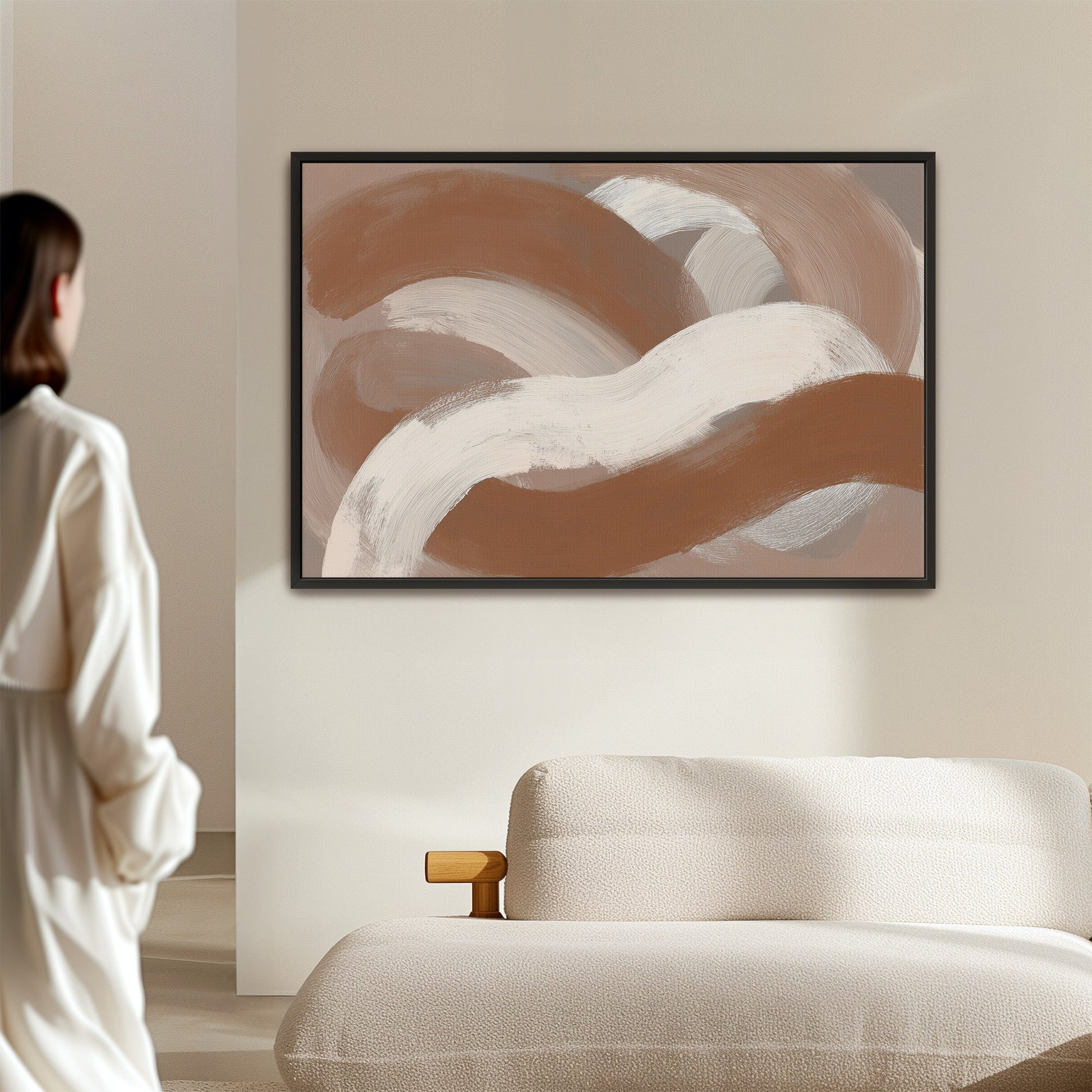 Abstract "Current" canvas print with taupe, ivory, and sienna brushstrokes in a black frame above a beige sofa
