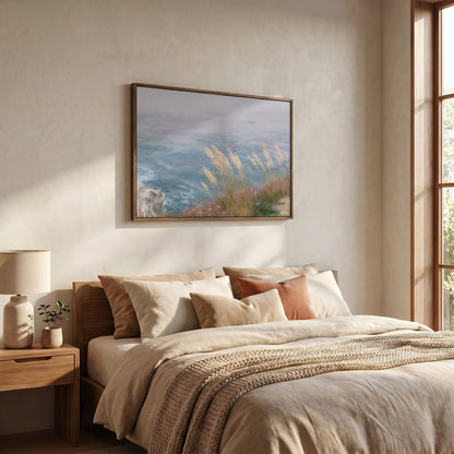 a serene bedroom scene with a large bed adorned with beige bedding and a framed painting of a coastal landscape hanging above it.
