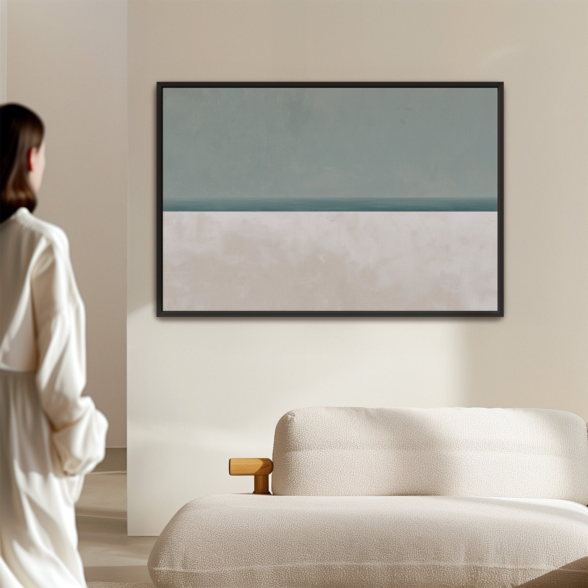 Minimalist Azure canvas print with tranquil sea and sky in muted sage and sand hues above beige sofa in modern living room