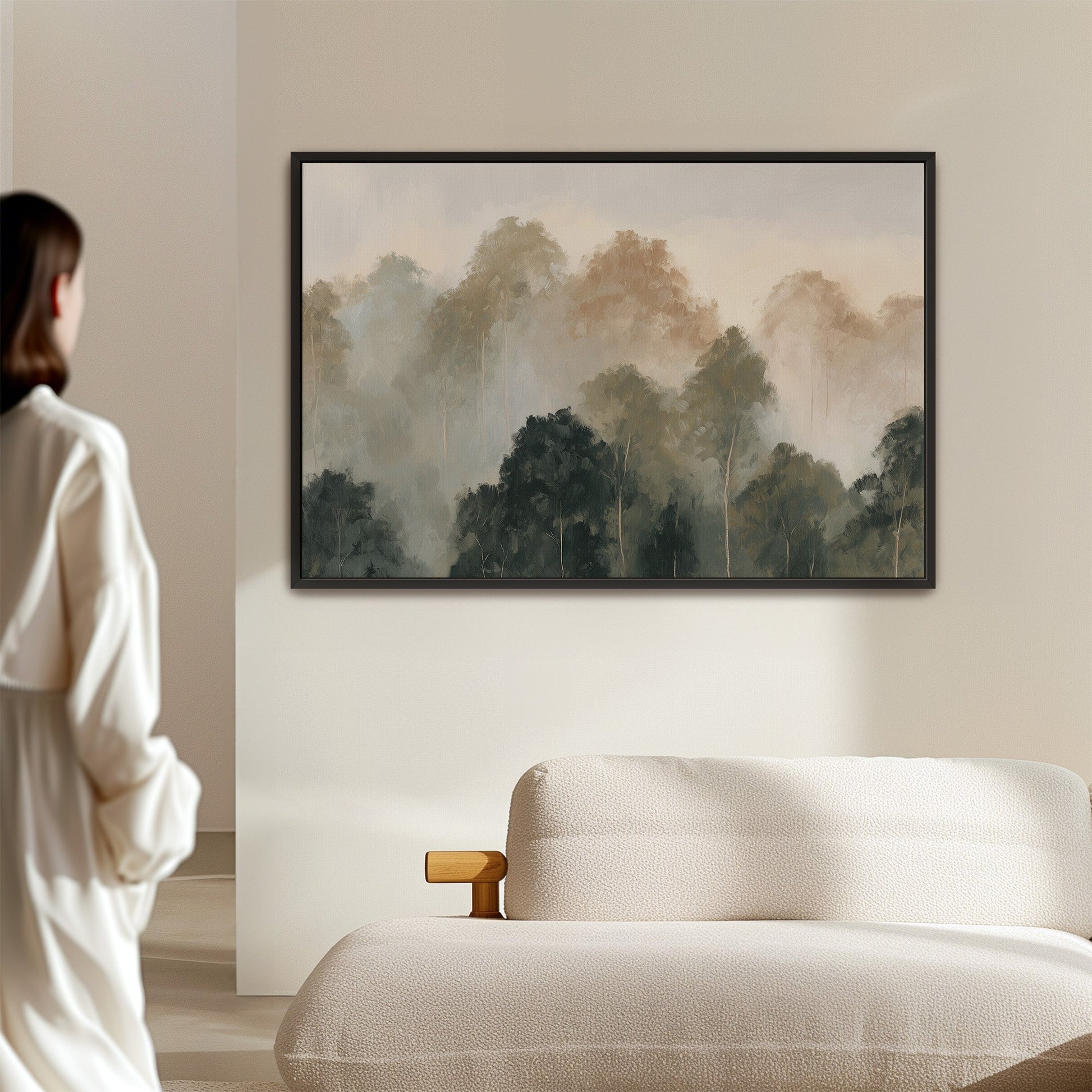 Fable Canvas Print depicting misty layered treetops in muted olive and ivory tones, framed and hung above a modern sofa in a minimalistic room