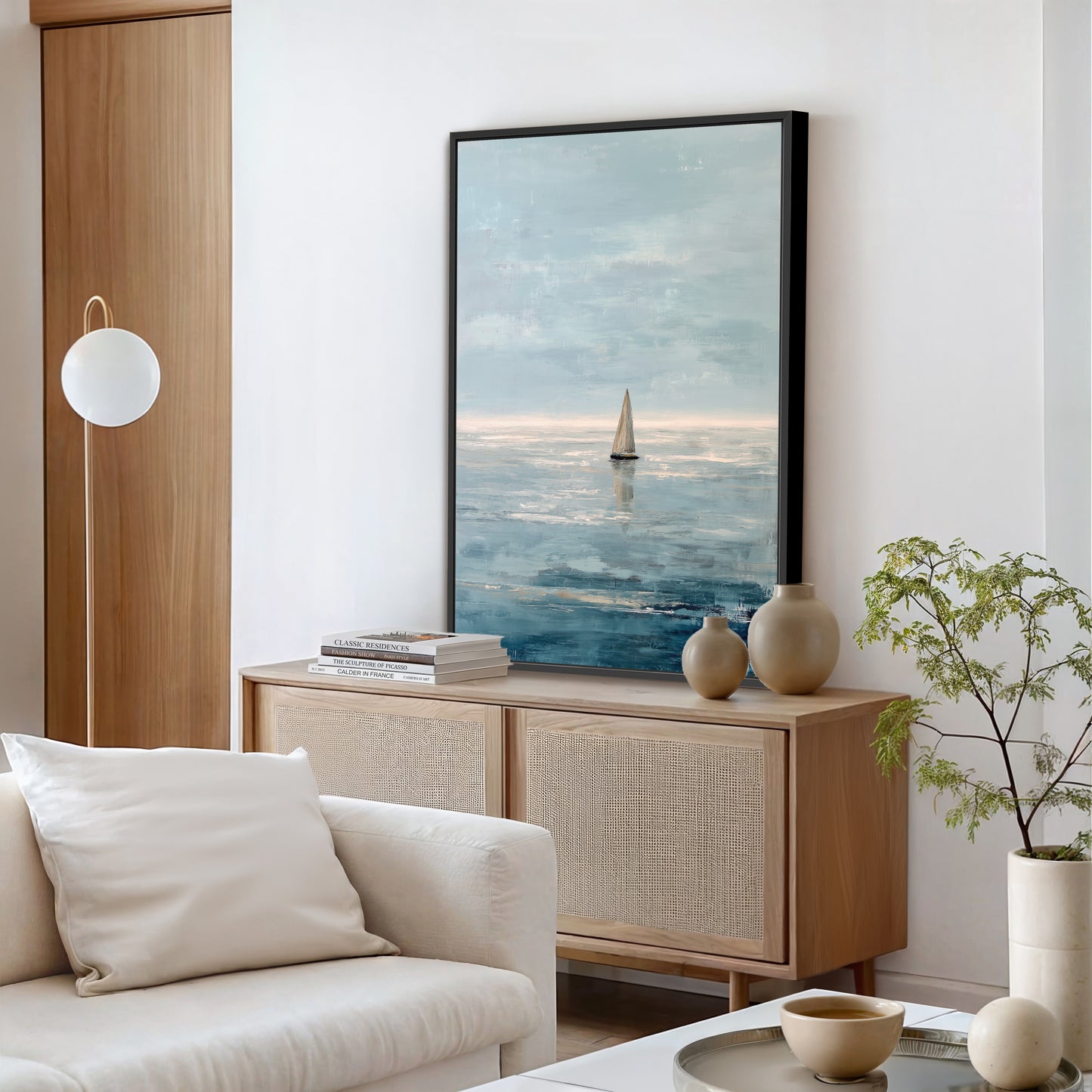 a serene living room with a large painting of a sailboat on the wall, a white sofa, a wooden cabinet, and a potted plant.