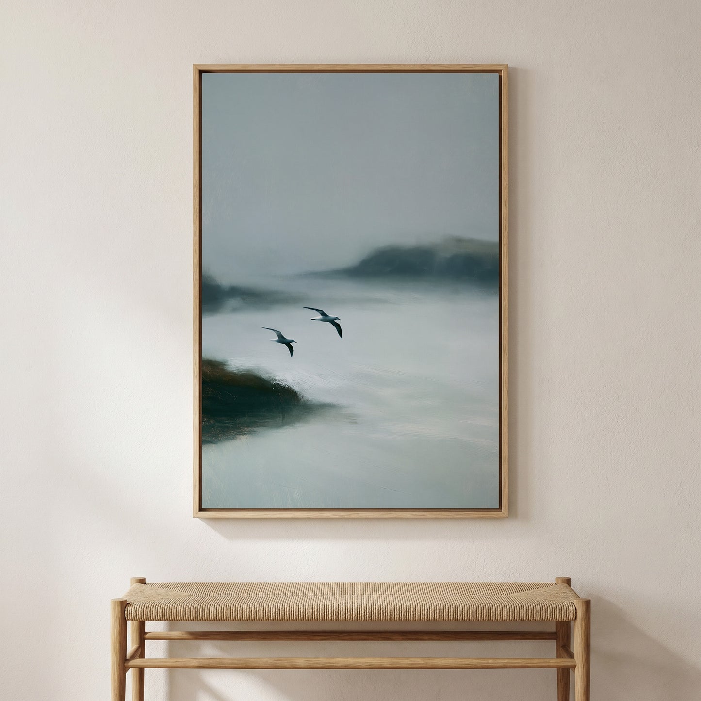 a large painting of two birds flying over a misty landscape, hanging on a wall above a wooden bench.