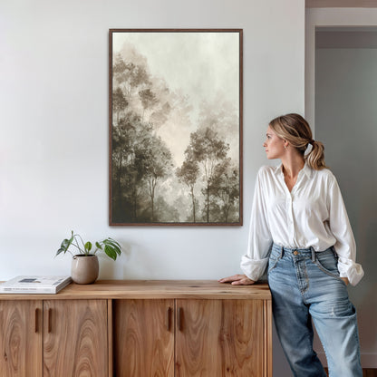 A woman in a white blouse and blue jeans stands in a room, leaning against a wooden cabinet, with a framed landscape painting hanging on the wall above her.