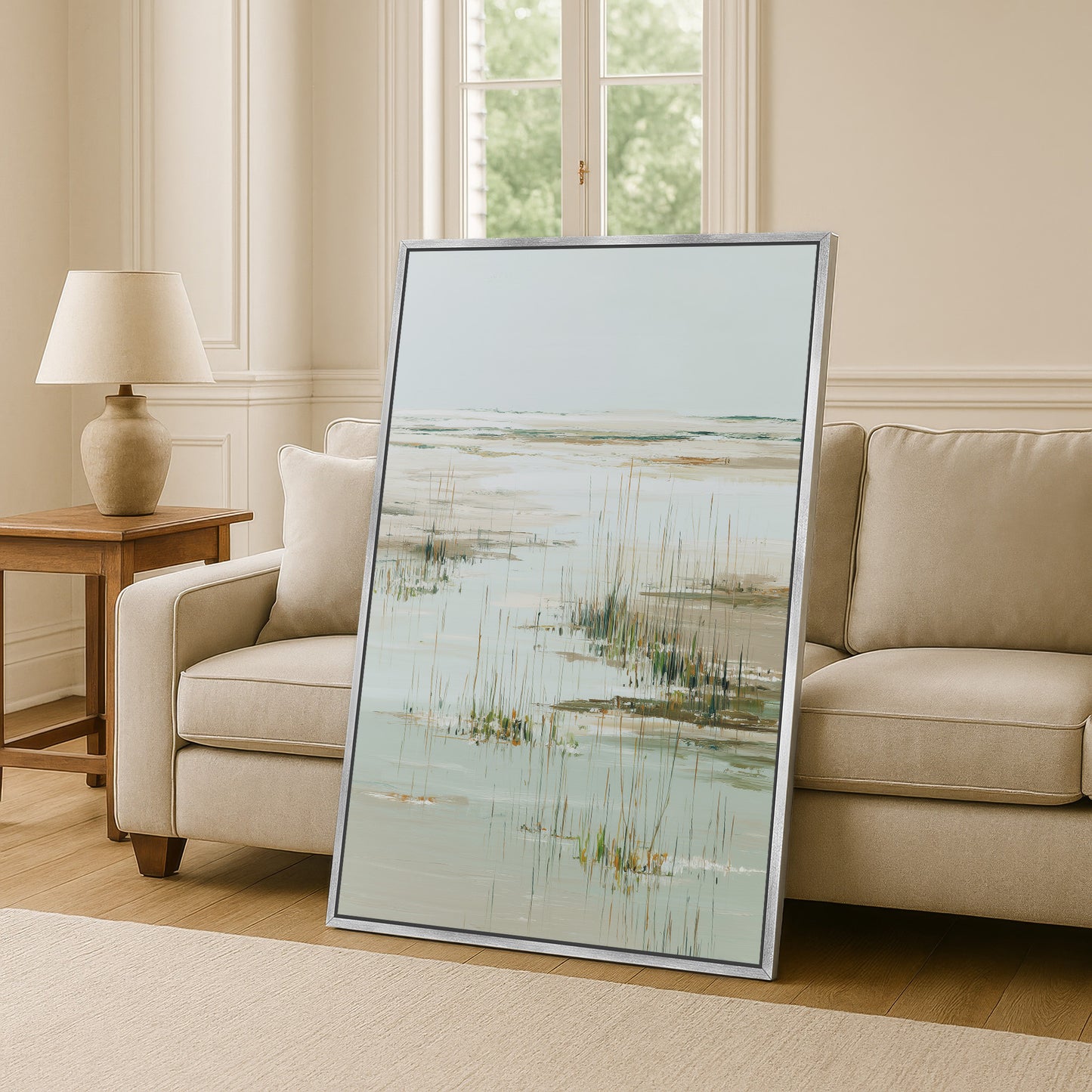a large framed painting of a serene landscape, including a body of water and tall grasses, displayed in a living room setting.