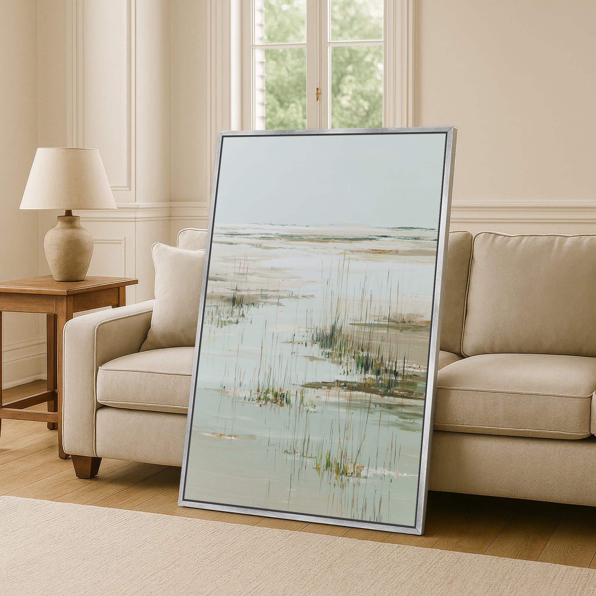 a large framed painting of a serene landscape, including a body of water and tall grasses, displayed in a living room setting.