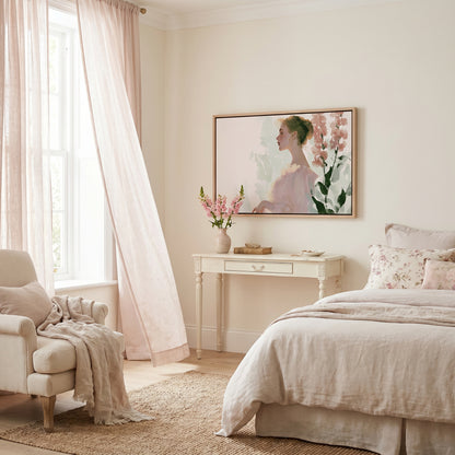 a serene and cozy bedroom with a large bed, a white dresser, and a framed painting of a woman. The room is decorated in a soft, pastel color palette, creating a warm and inviting atmosphere.