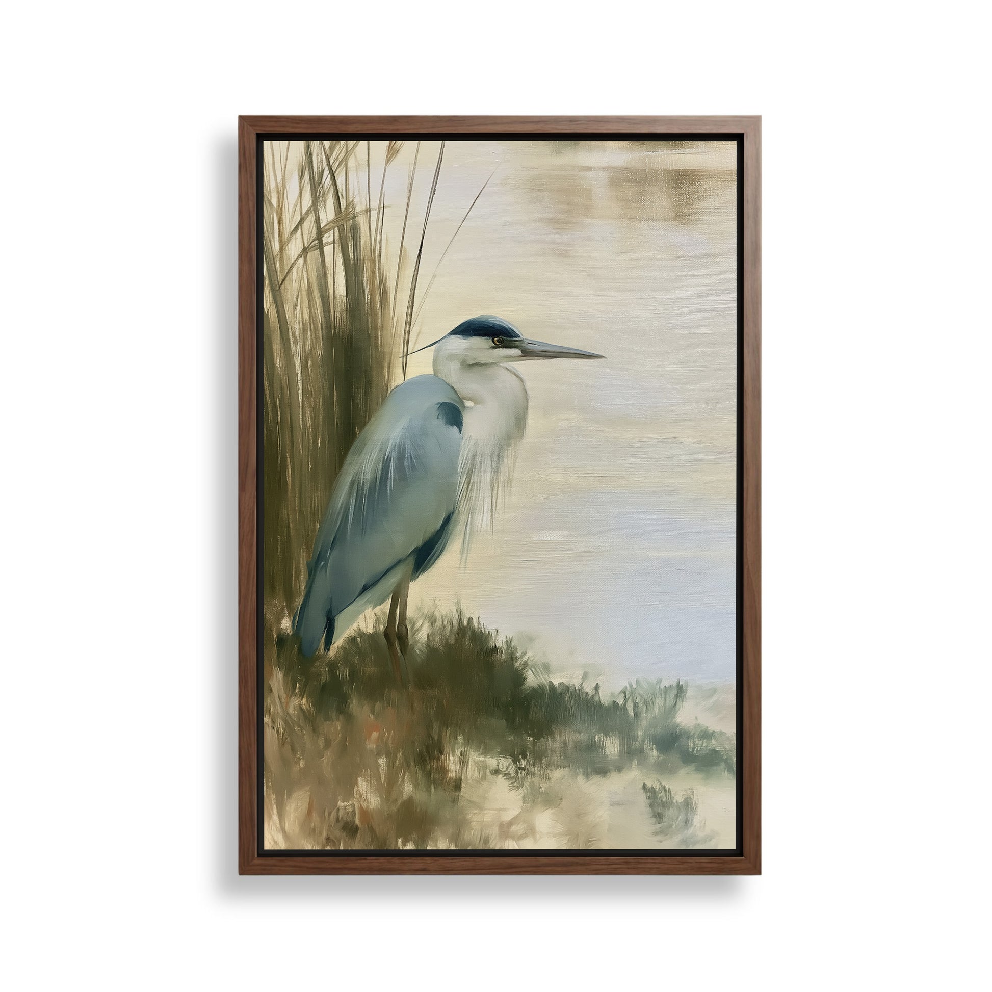 A framed painting depicting a blue heron standing on the bank of a body of water, surrounded by tall grasses.