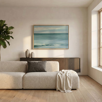 a serene living room with a large window, a white sofa, a wooden cabinet, and a framed painting of a tranquil ocean scene.