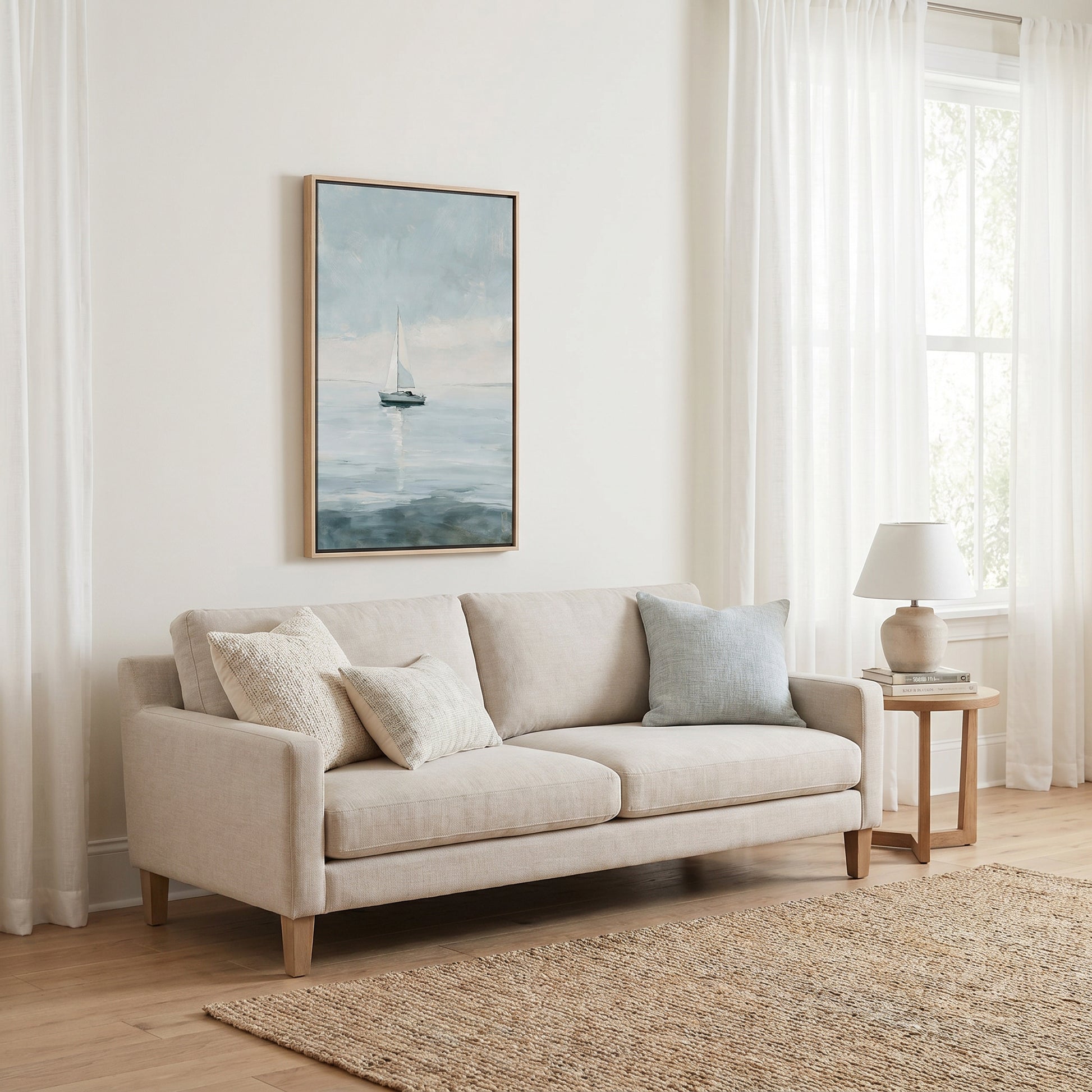 a cozy living room with a beige sofa adorned with two throw pillows, a wooden side table with a lamp, and a framed painting of a sailboat on the wall.