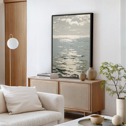 a modern living room with a large framed artwork of a seascape hanging on the wall above a wooden cabinet. The room is furnished with a white sofa, a coffee table, and a potted plant, creating a serene and inviting atmosphere.