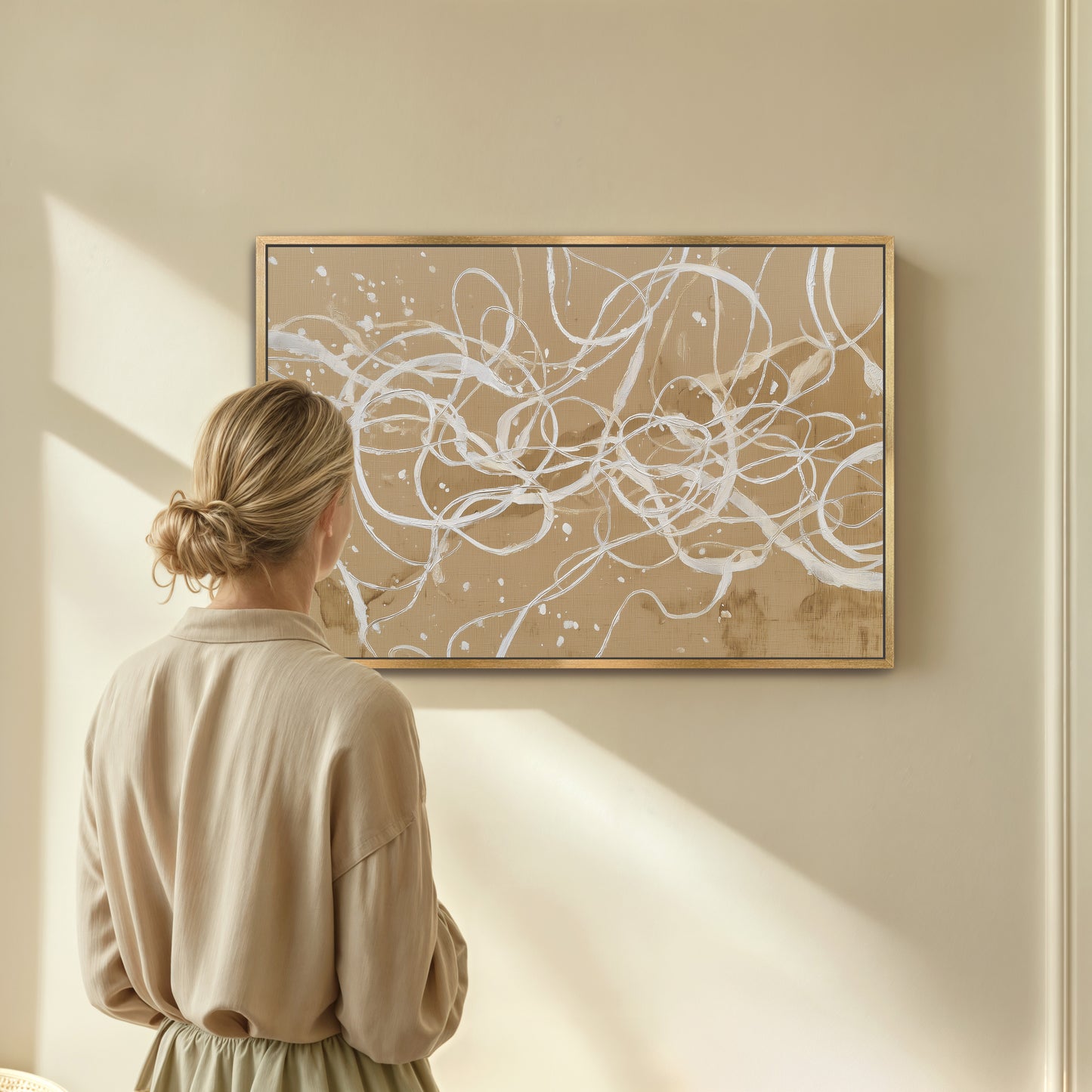 Woman admiring abstract ivory linework canvas in natural wood frame