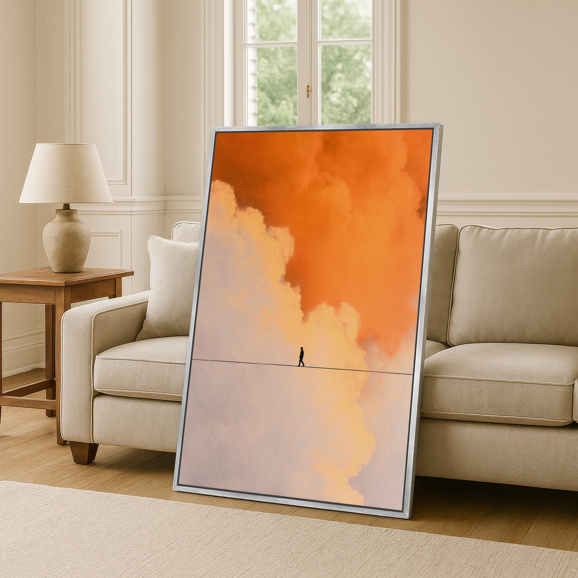 Modern canvas print with vibrant orange and cream clouds leaning against a sofa in an elegant light-toned living room.