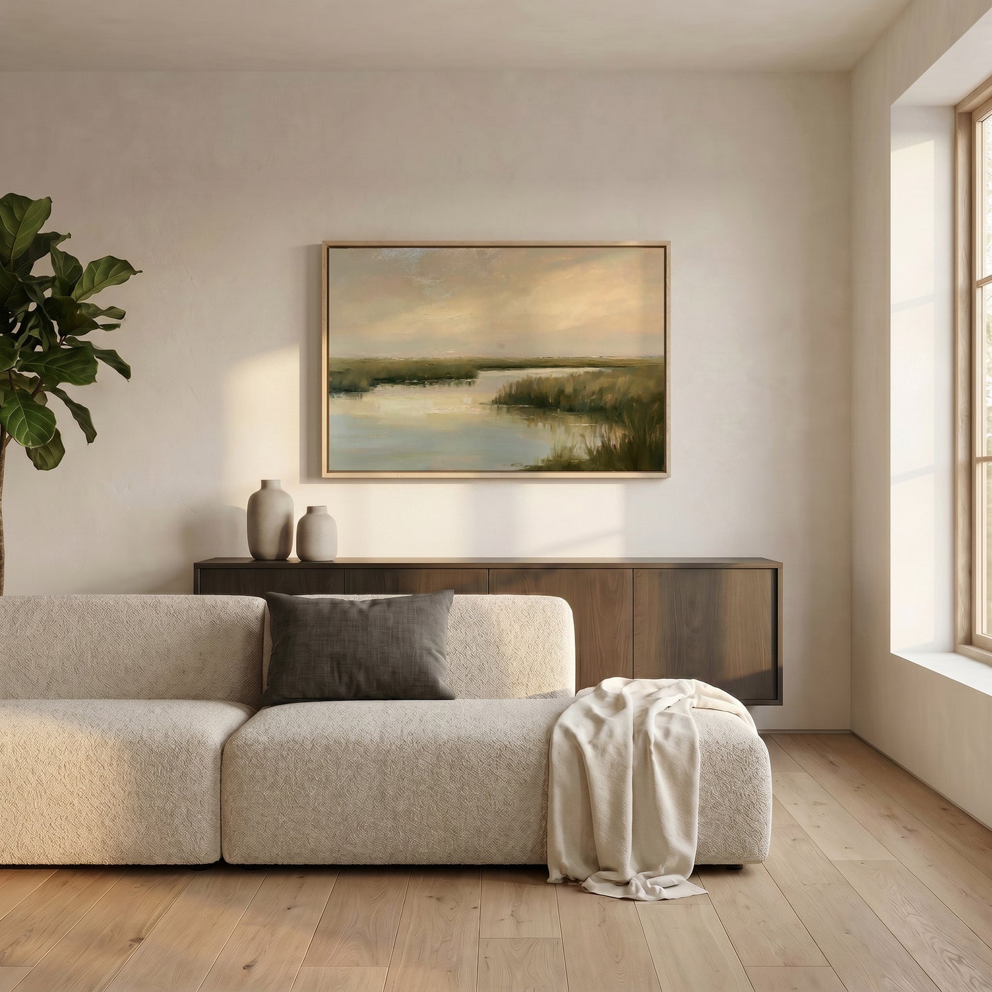 a serene living room with a large window, a white sofa, a wooden cabinet, and a framed landscape painting hanging on the wall.