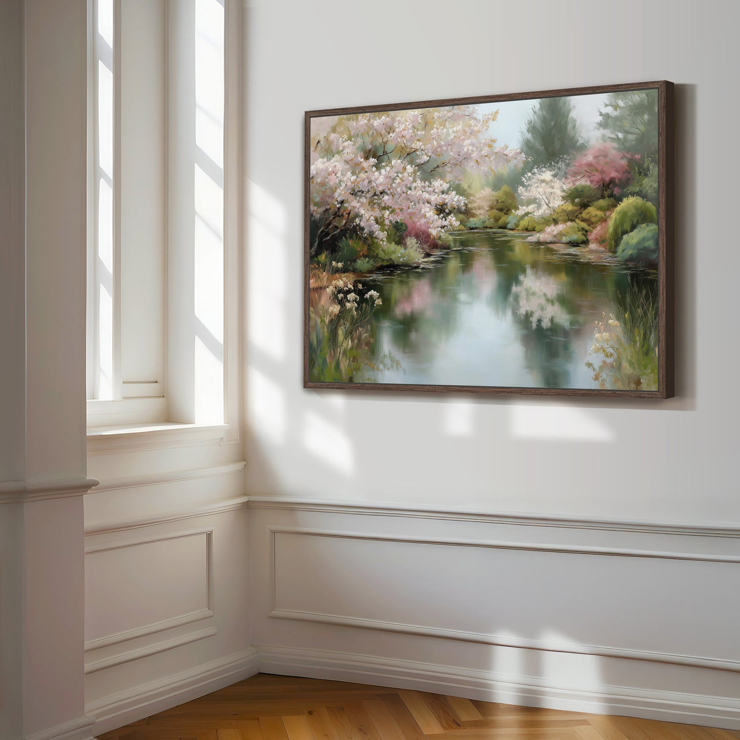 a large, framed painting of a serene landscape with a pond and blooming trees, hanging on a white wall in a room with a window.