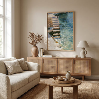 a cozy living room with a beige sofa, a wooden sideboard, and a large framed painting of a staircase leading to a pool.