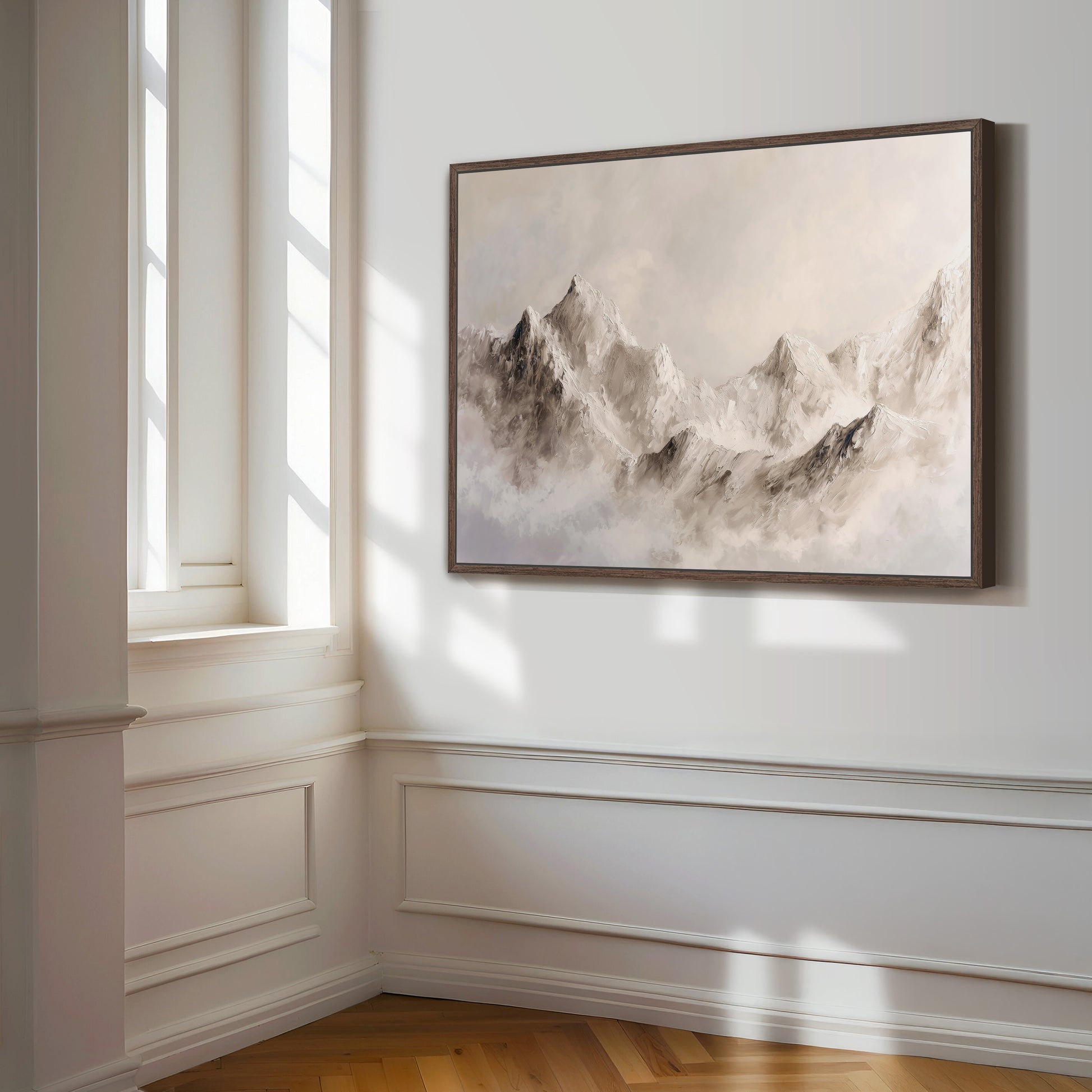 a large, framed painting of a mountain landscape hanging on a white wall in a room with a window.
