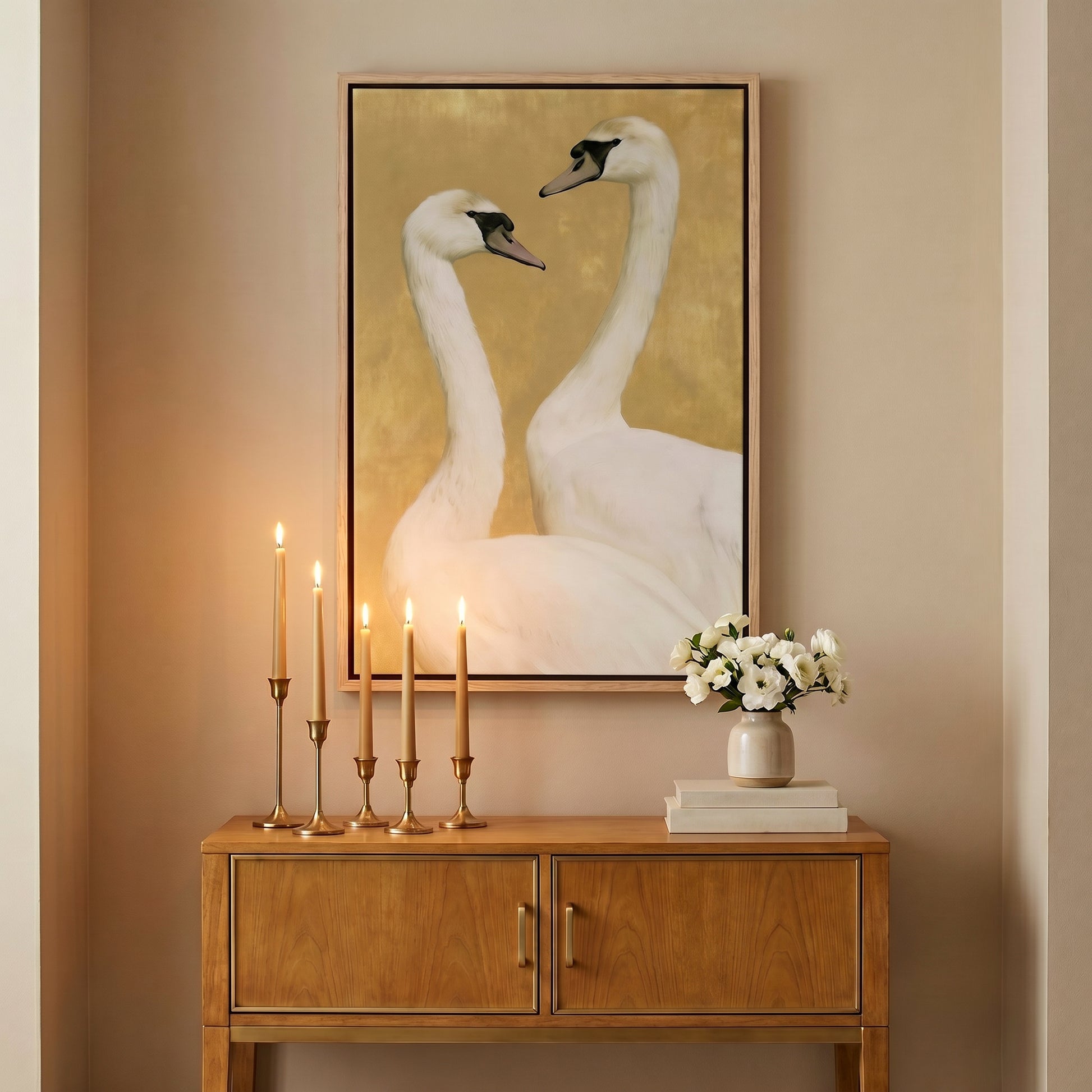 a wooden cabinet with a vase of flowers and a framed picture of two swans on the wall above it.