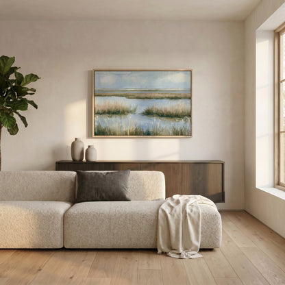 a serene living room with a large window, a beige sofa, a wooden cabinet, and a framed landscape painting on the wall.