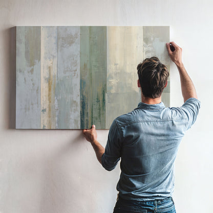 A man is hanging a large abstract painting on a wall.