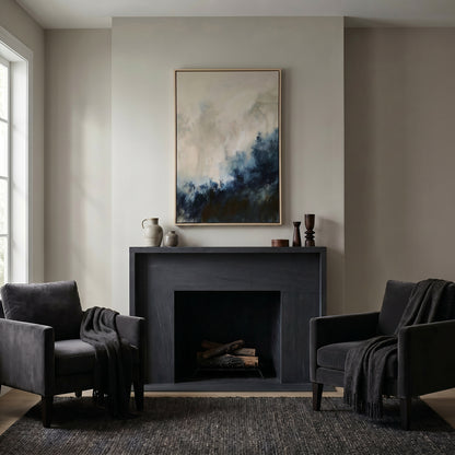 a cozy living room with a fireplace, two black armchairs, and a large abstract painting hanging above the fireplace.