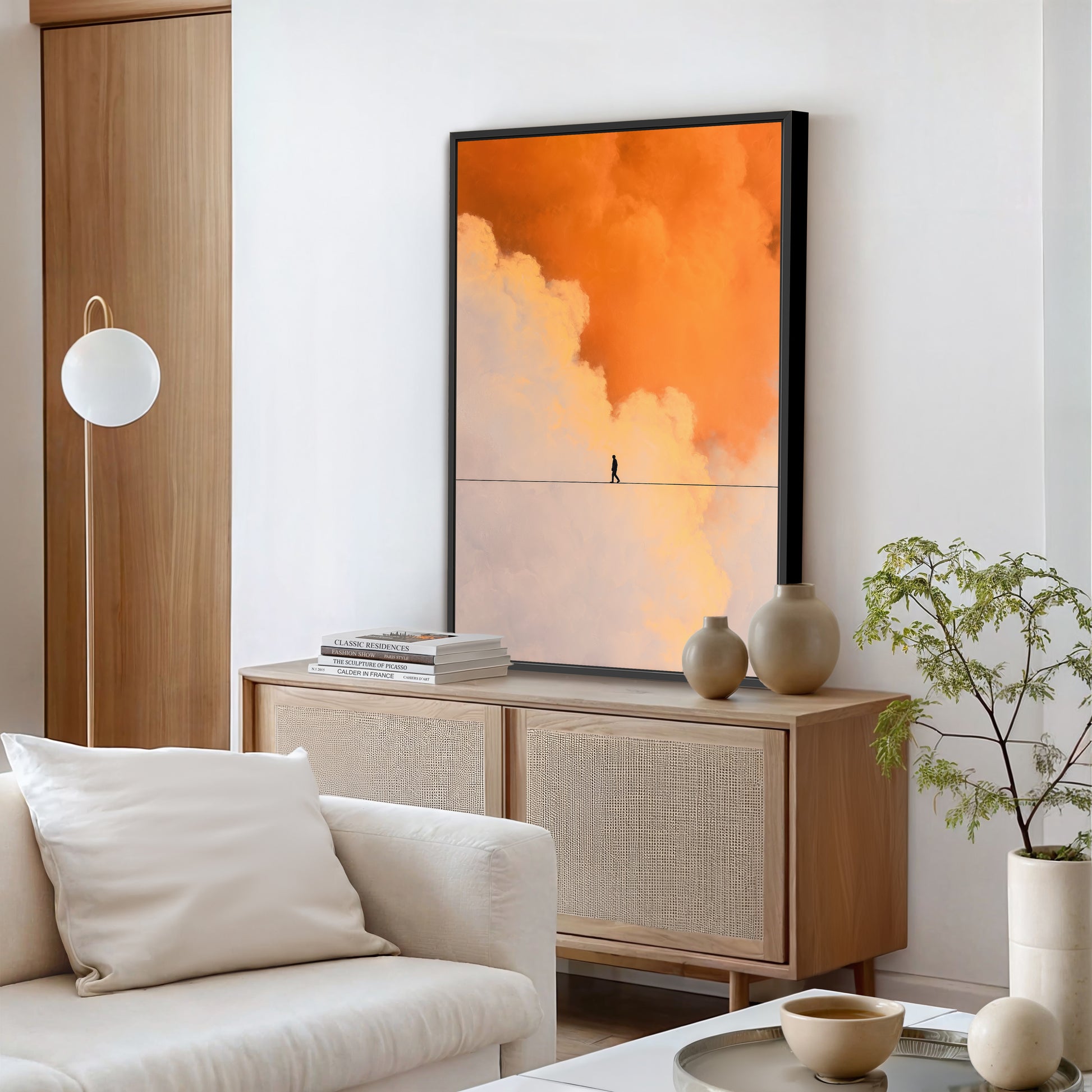 Minimalist interior with framed orange cloud artwork above wooden console and decorative vases in a bright living space.