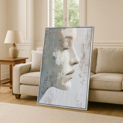 a large framed painting of a woman's face, displayed in a living room setting with a couch and a lamp visible in the background.