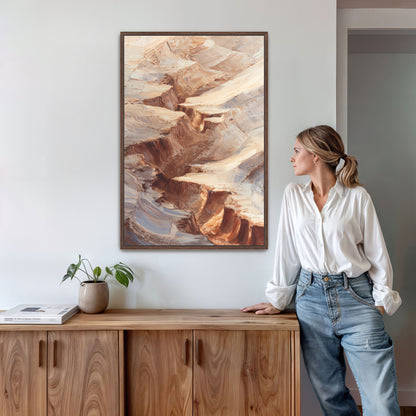 A woman in a white shirt and blue jeans stands in a room, leaning against a wooden cabinet, with a framed painting of a rocky landscape hanging on the wall behind her.