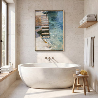 a serene and modern bathroom with a large white freestanding bathtub, a wooden stool, and a framed painting of a staircase leading to a pool of water.