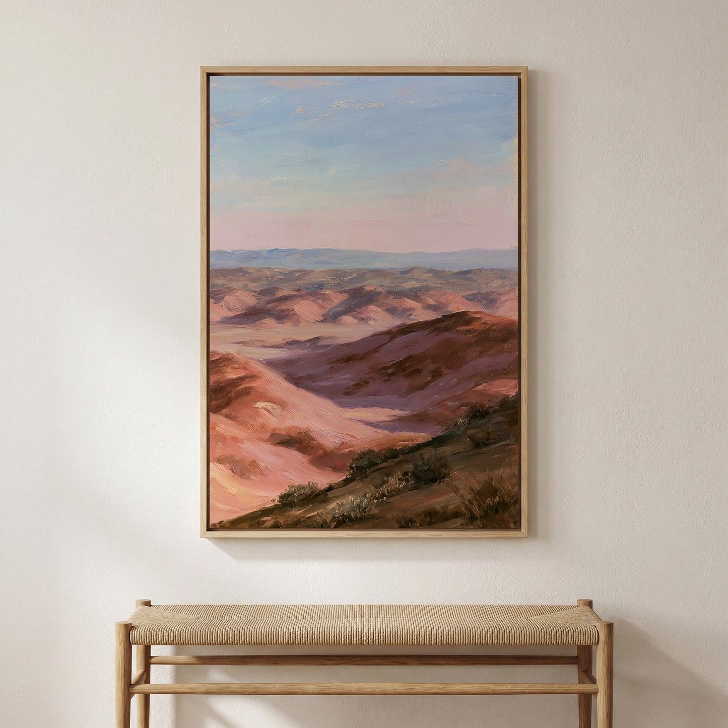 a large painting of a mountainous landscape hanging on a wall, with a bench below it.