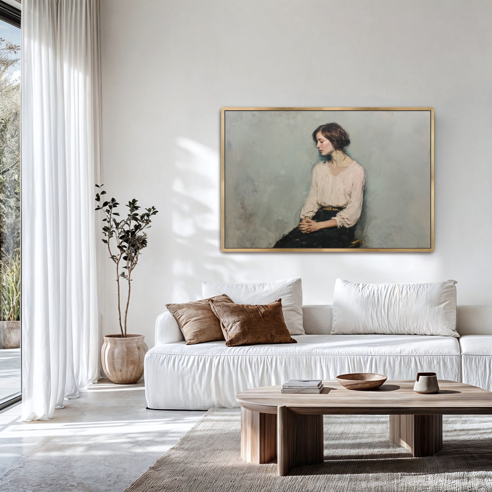 Oversized contemplative portrait in a gold frame above a modern white sofa with earthy decor.