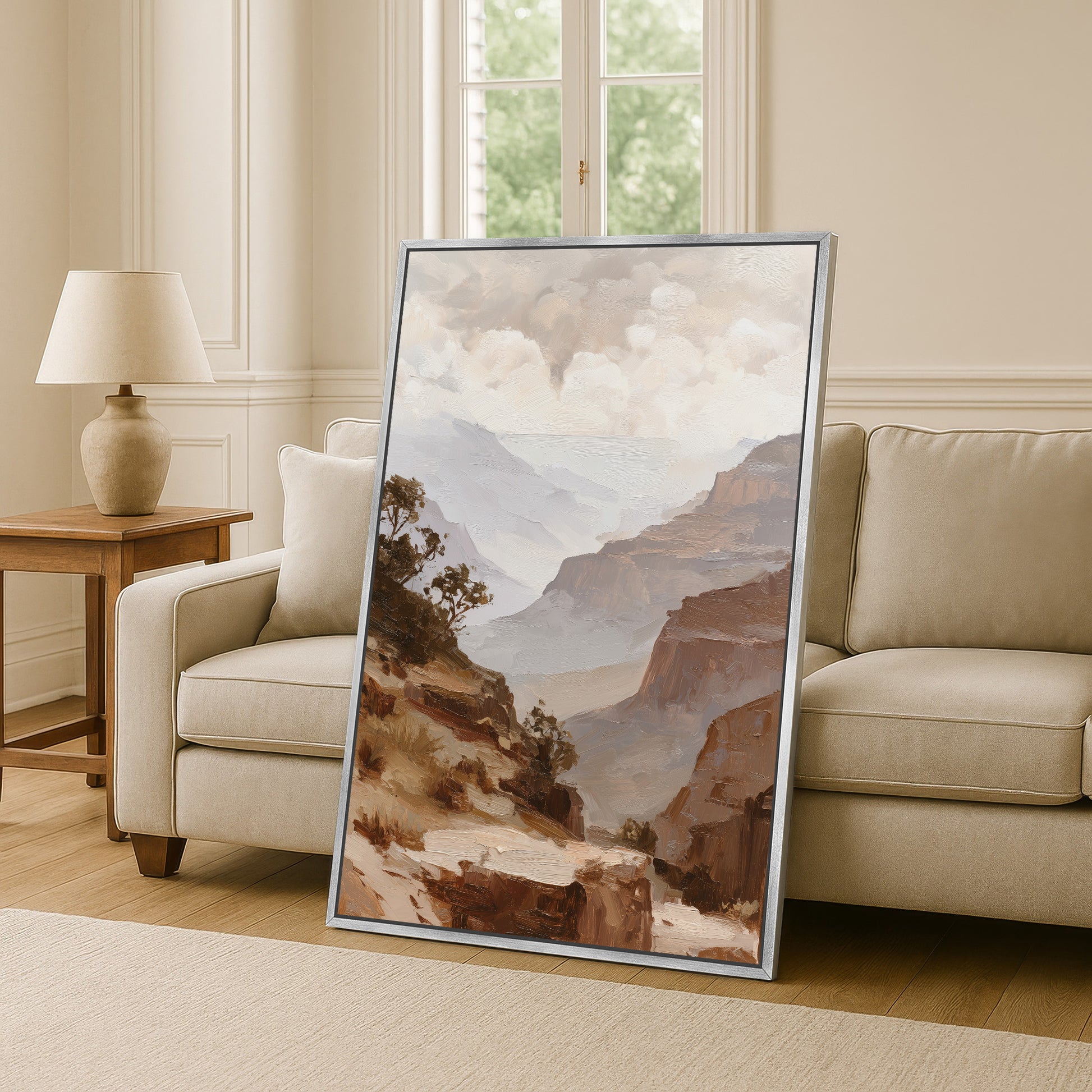 a large framed painting of a mountainous landscape, with a beige sofa and a wooden side table in the background.