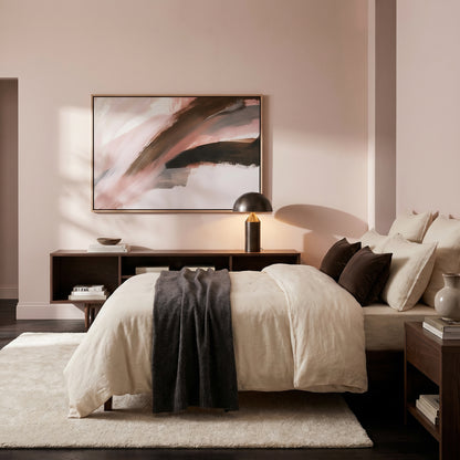 a serene and modern bedroom with a large bed, a wooden nightstand, and a framed abstract painting on the wall.