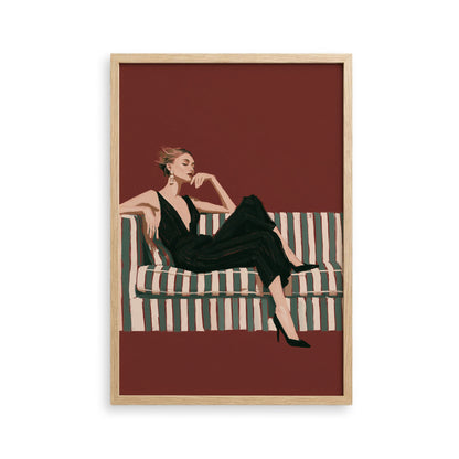 A woman in a black jumpsuit is sitting on a striped couch, with her hand on her chin.