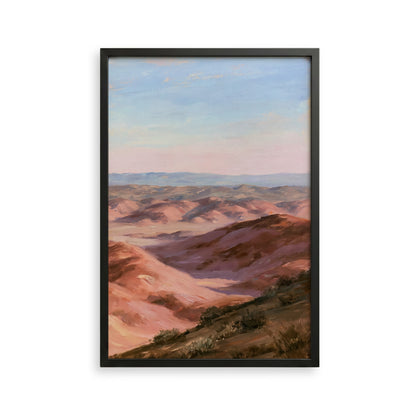 The image is a framed painting depicting a scenic landscape with rolling hills and a clear blue sky.