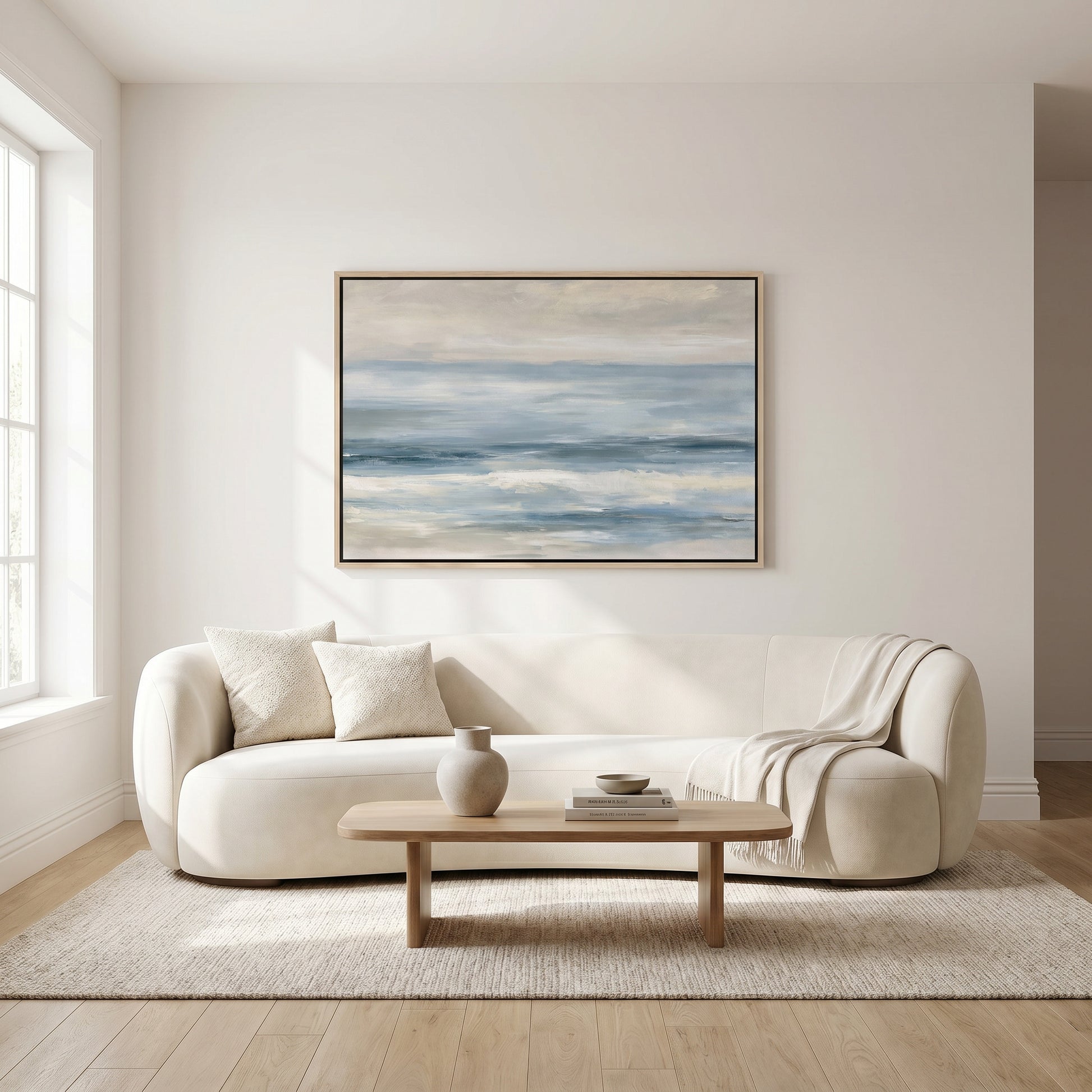a modern living room with a large white sofa, a wooden coffee table, and a framed painting of a serene landscape hanging on the wall above the sofa.