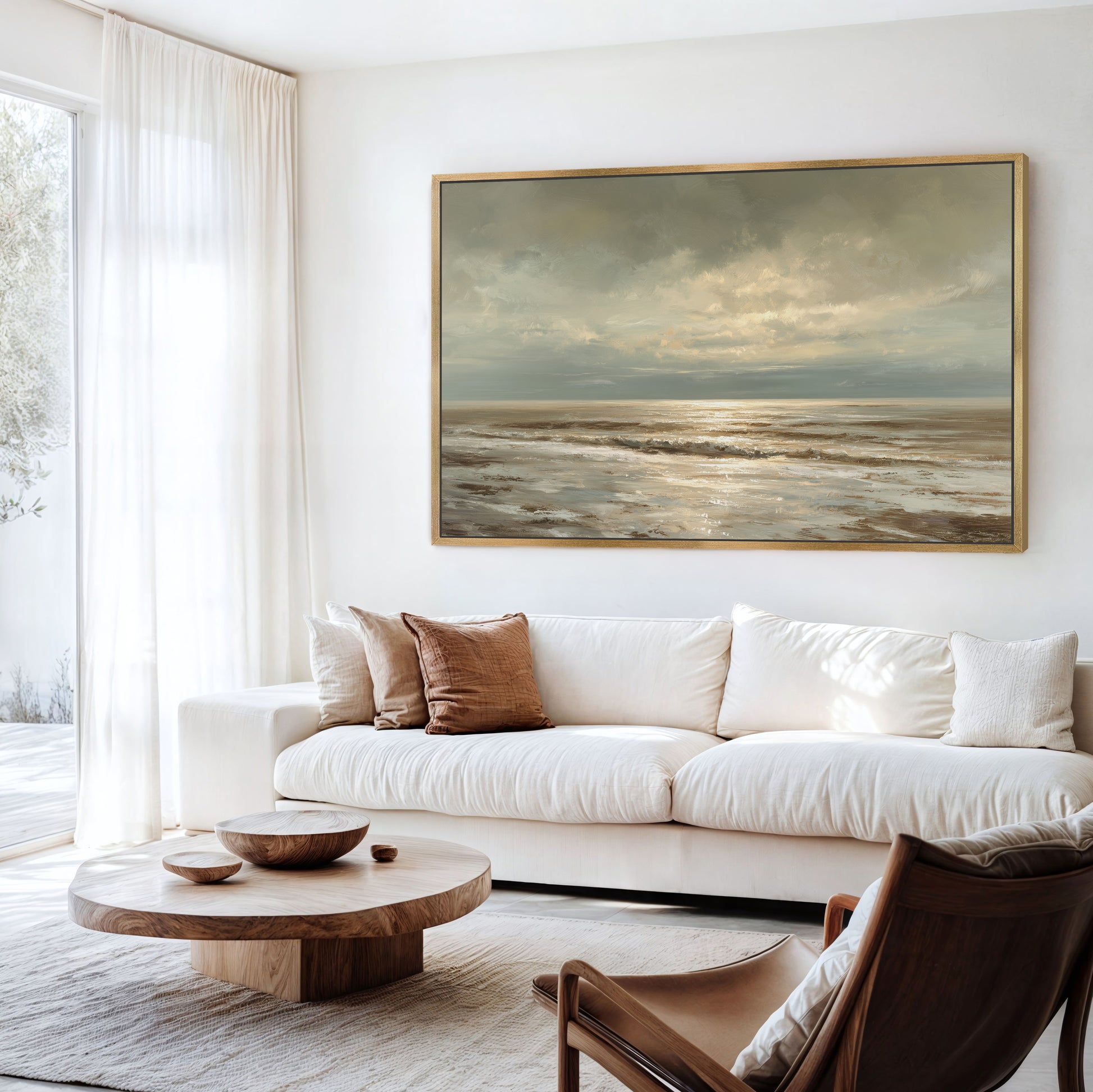 a serene living room with a large painting of a tranquil ocean scene hanging on the wall. The room is furnished with a white sofa, a wooden coffee table, and a brown leather armchair. The overall atmosphere of the room is calm and inviting, with the painting serving as a focal point.