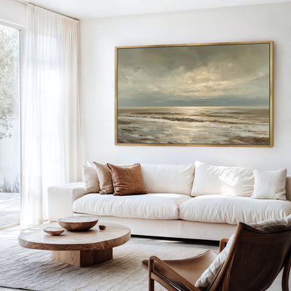a serene living room with a large painting of a tranquil ocean scene hanging on the wall. The room is furnished with a white sofa, a wooden coffee table, and a brown leather armchair. The overall atmosphere of the room is calm and inviting, with the painting serving as a focal point.