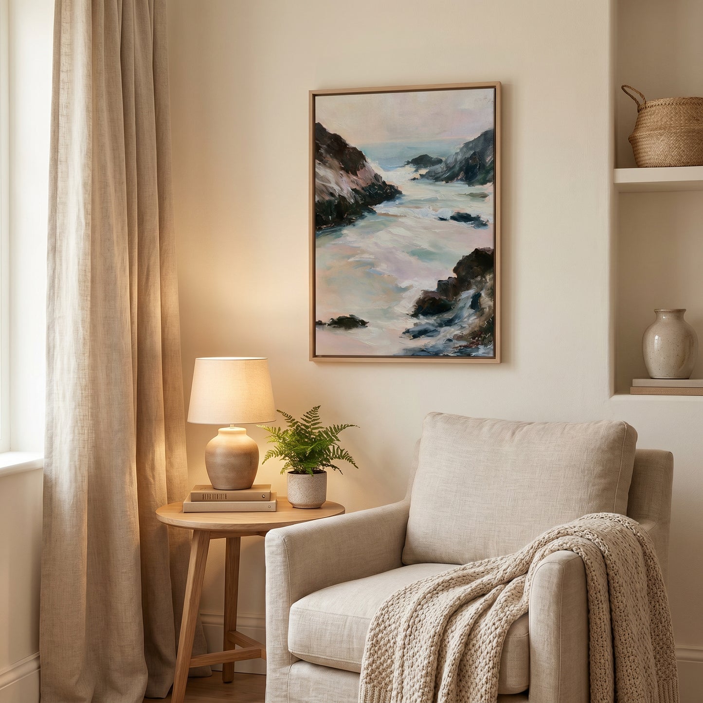 a cozy living room with a beige armchair, a wooden side table with a lamp and a plant, and a framed painting of a coastal landscape hanging on the wall.