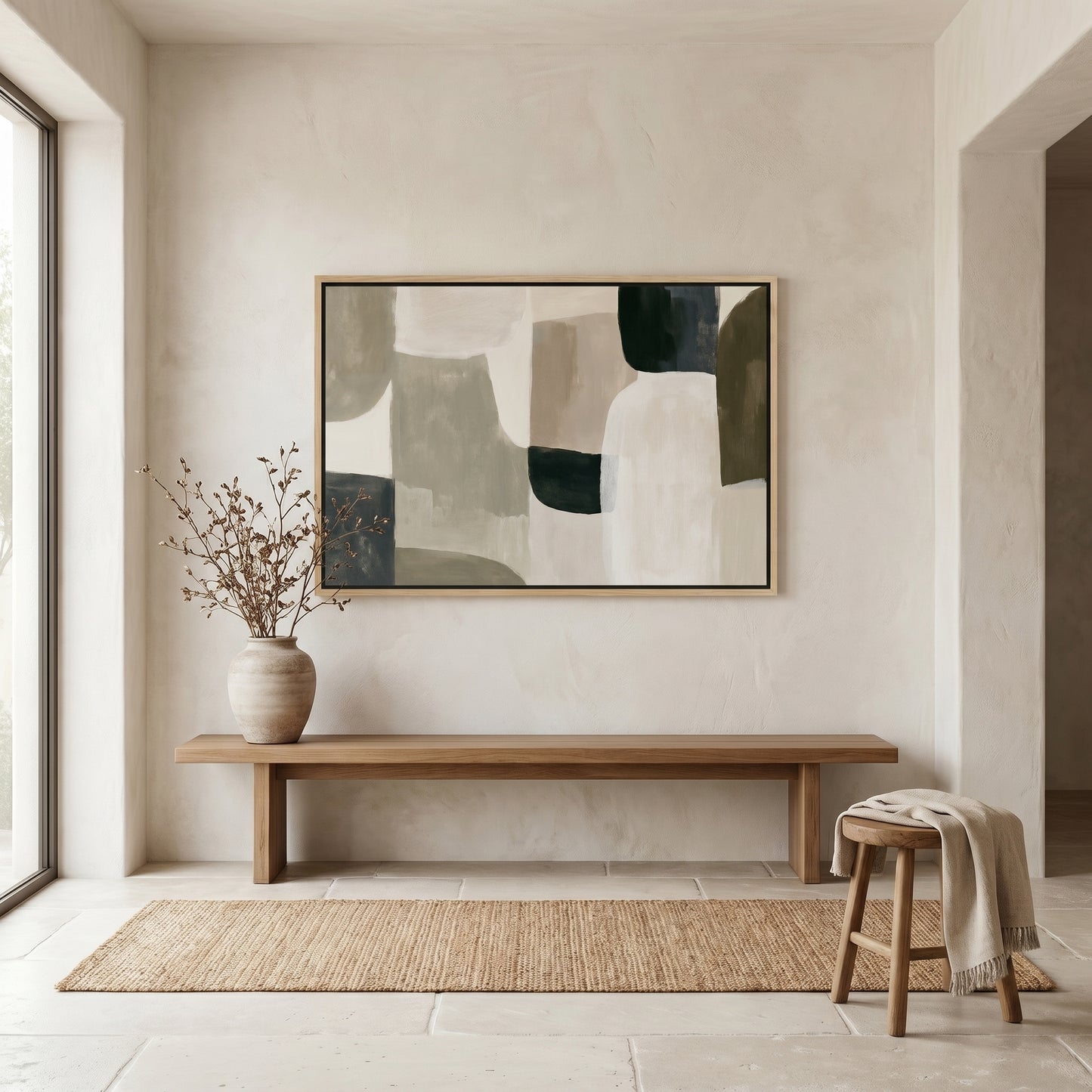 a minimalist interior design with a large abstract painting hanging on a white wall above a wooden bench. The painting is predominantly gray and white, with some green and brown accents. A vase with dried branches is placed on the bench, and a woven rug is spread out on the floor in front of the bench.