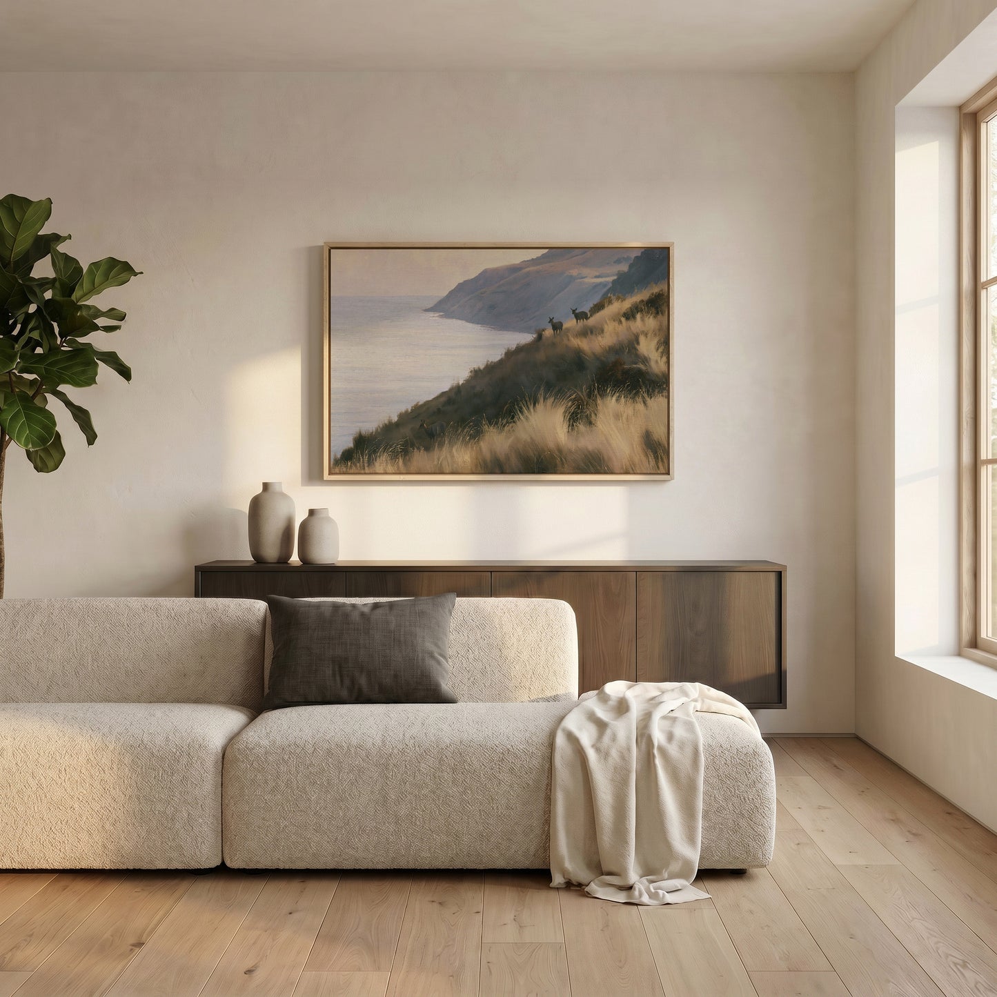 a serene living room with a large window, a beige sofa, a wooden cabinet, and a framed landscape painting hanging on the wall.