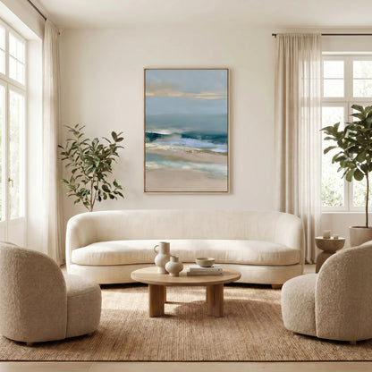 a serene living room with a large painting of a beach scene hanging on the wall. The room is furnished with a white sofa, two armchairs, and a wooden coffee table. The room is decorated with potted plants and vases, creating a calm and inviting atmosphere.
