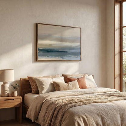 a serene bedroom scene with a large bed adorned with beige bedding and a wooden headboard. Above the bed, a framed landscape painting hangs on the wall, adding an artistic touch to the room. The room is well-lit, with natural light streaming in from a window on the right side, creating a warm and inviting atmosphere.