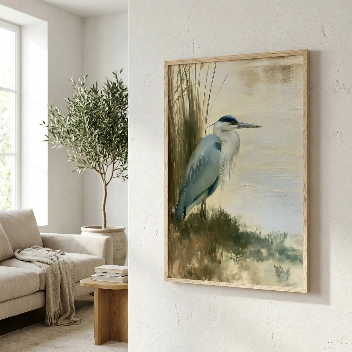 a framed painting of a blue heron standing in a grassy field, with a cozy living room scene in the background.
