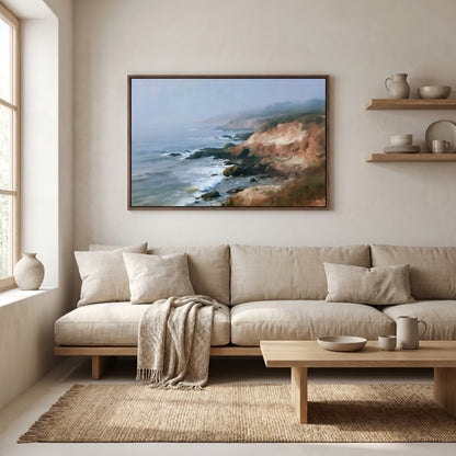 a serene living room with a large framed painting of a coastal landscape hanging on the wall above a beige sofa. The sofa is adorned with a throw blanket and a wooden coffee table. The room also features a window, shelves displaying decorative items, and a rug on the floor.
