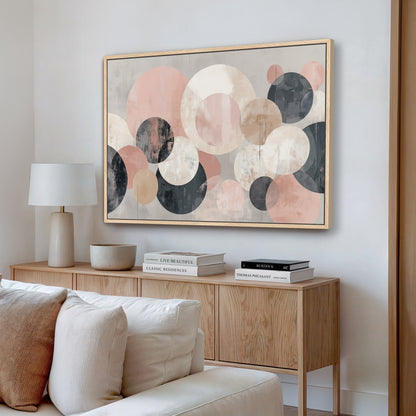 a living room with a large abstract painting hanging on the wall above a wooden cabinet. The cabinet has a bowl and a stack of books on it. The room also includes a white couch and a lamp.