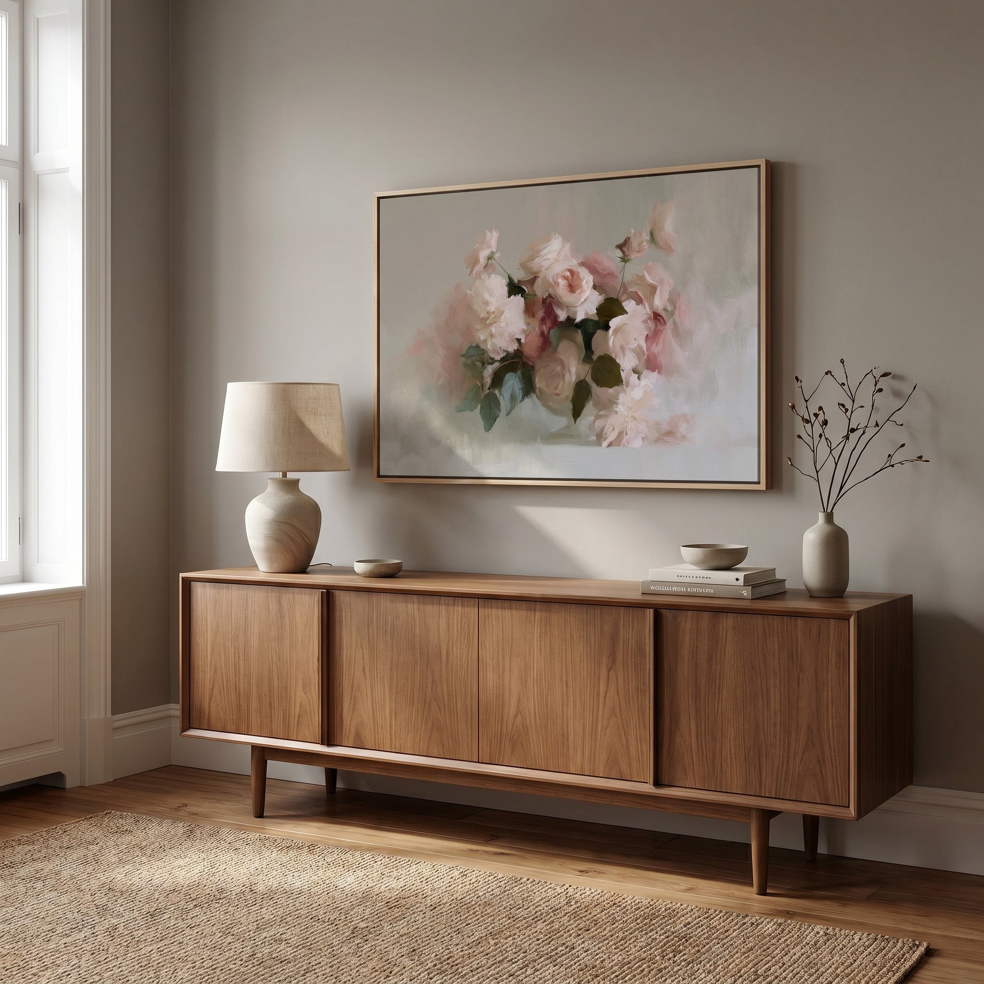 a wooden cabinet with a framed painting of pink flowers hanging above it, along with a lamp and a small plant on the cabinet.