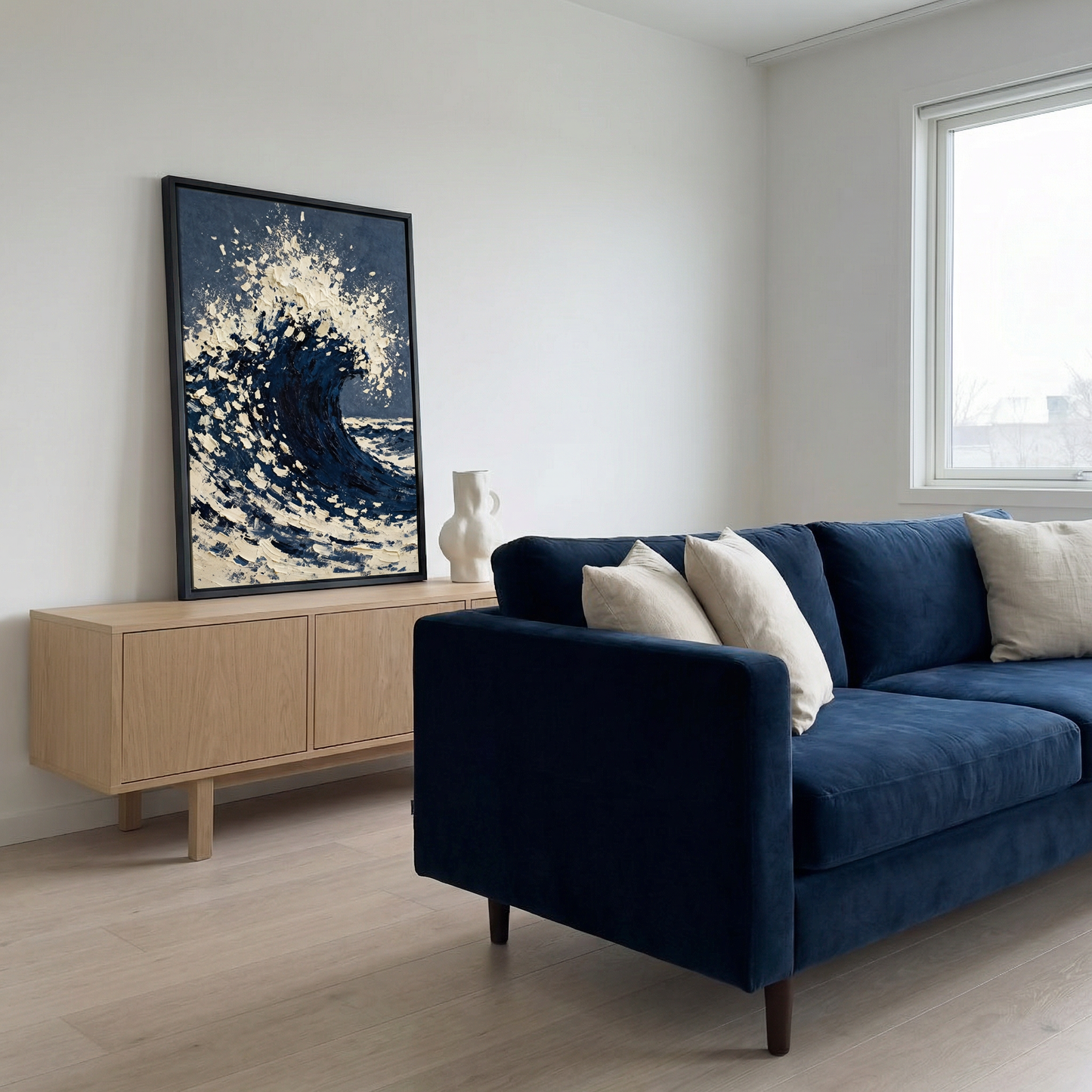 a living room with a blue sofa, a wooden cabinet, and a framed artwork depicting a large wave.