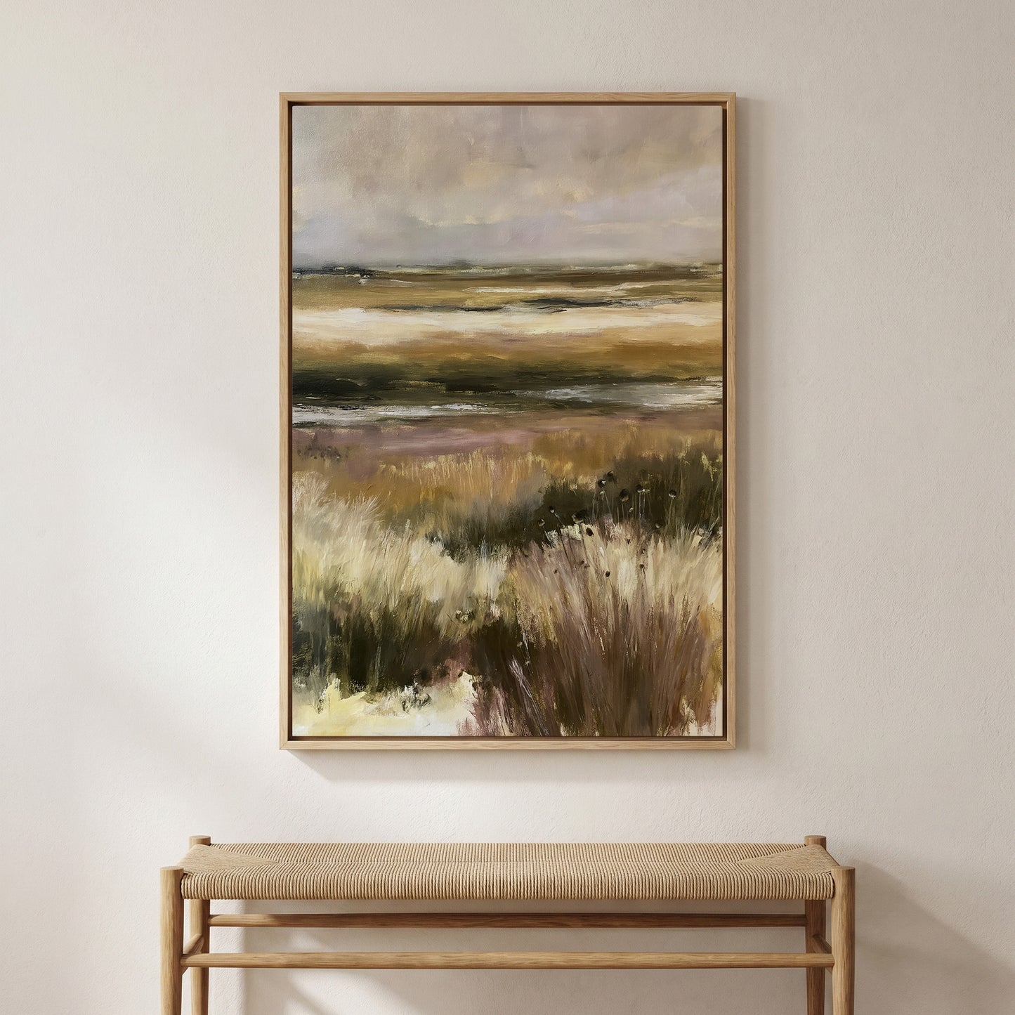a large landscape painting hanging on a wall above a wooden bench.